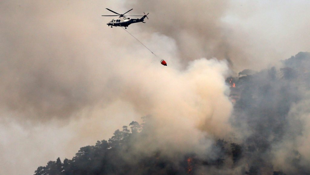epa05381388 A helicopter drops water on a forest fire in the Troodos mountain area of Cyprus, 21 June 2016. Three aircraft from France and one from Italy will join Cypriot firefighters in the battle to control some of the worst forest fires to have hit the island. Cyprus has asked for assistance from the EU Civil Protection Mechanism in order to contain and extinguish a massive fire which broke out on Sunday in the Evrychou area, in Solea region, in Nicosia district. The fire has so far caused huge environmental damage. EPA/KATIA CHRISTODOULOU