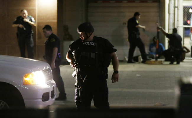 Dallas police detain a driver after several police officers were shot in downtown Dallas, Thursday, July 7, 2016. Snipers apparently shot police officers during protests and some of the officers are dead, the city's police chief said in a statement. (AP Photo/LM Otero)