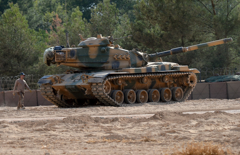 A Turkish tank stationed near the Syrian border, in Karkamis, Turkey, Monday, Aug. 29, 2016. Turkey's state-run news agency says three rockets fired from Syria have hit Turkish border town of Kilis, injuring five children, Turkish President Recep Tayyip Erdogan says Turkey will press ahead with its military operations in Syria until the Islamic State group and Kurdish militants no longer pose a security threat. Erdogan said Turkey was determined to take all steps necessary both inside Turkey and abroad to protect Turkish citizens.(Ismail Coskun/IHA via AP)