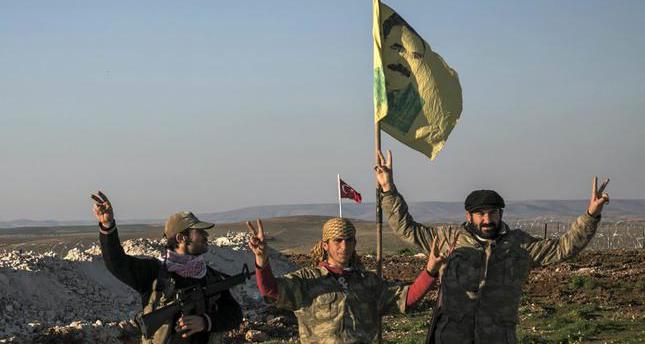 FILE - In this Feb. 22, 2015, file photo, Syrian Kurdish militia members of the YPG make a V-sign next to a drawdng of Abdullah Ocalan, jailed Kurdish rebel leader, in Esme village in Aleppo province, Syria. U.S.-backed Kurdish forces have forcefully displaced thousands of Syrian civilians, mostly Arabs, and demolished villages in northern Syria, often in retaliation for the residents' perceived sympathies for the Islamic State group and other militants, Amnesty International said Tuesday, Oct. 13. (Mursel Coban/Depo Photos via AP, File) *** Local Caption *** AS CONTRADICTORY STATEMENTS CONSECUTIVELY COME FROM THE U.S. OVER PROVIDING ARMS SUPPORT FOR THE PYD, WHILE THE PKK-LINKED GROUP CONFIRMED THE ISSUE. ANKARA'S CONCERNS HAVE ESCALATED SINCE AMERICAN WEAPONS WERE SEIZED AND STOCKPILED BY PKK